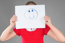 Foto Mädchen hält sich Blatt mit Smiley vors Gesicht