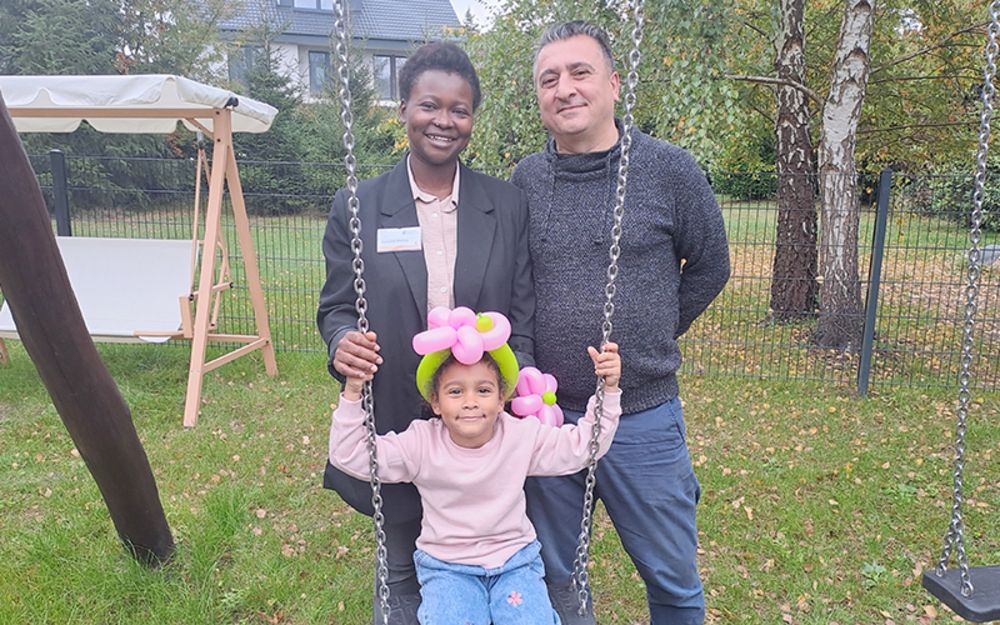 Foto zeigt Mitarbeiterin Catherine Nzembi mit ihrem Ehemann und ihrer kleinen Tochter im Garten an der Schaukel.