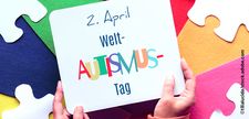 Foto zeigt Hände, die ein Schild mit der Aufschrift "2. April Welt-Autismus-Tag" hochhalten