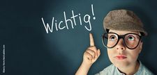 Foto zeigt einen Jungen mit Schirmmütze, der den Finger hebt und auf den Schriftzug "Wichtig" zeigt