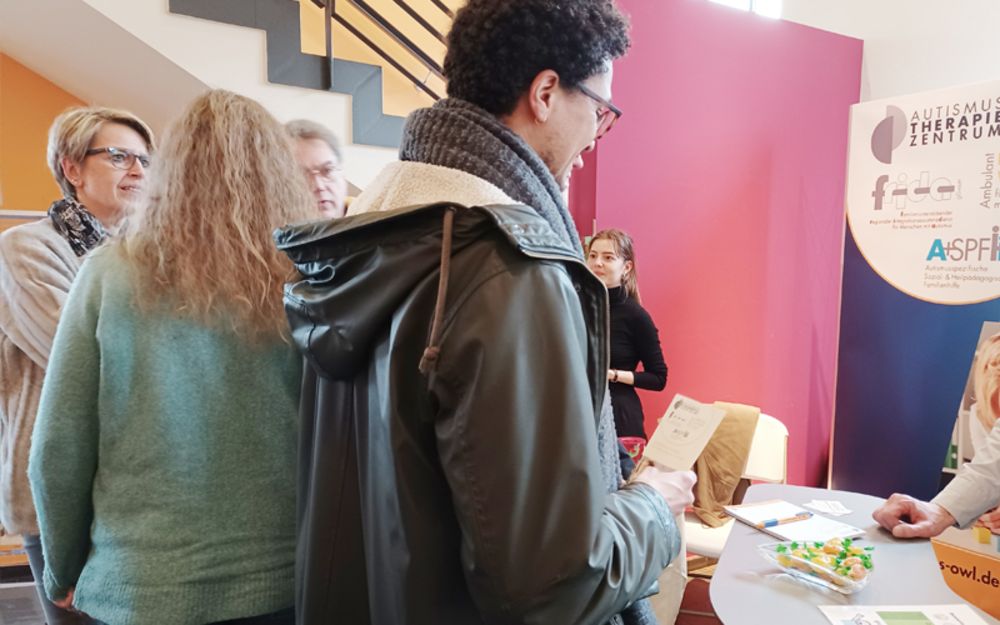 Foto zeigt Kolleginnen vom Autismus-Therapie-Zentrum und zwei Besucher der Veranstaltung im Gespräch