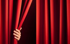 Foto zeigt einen roten Theatervorhang und eine Hand, die ihn aufzieht