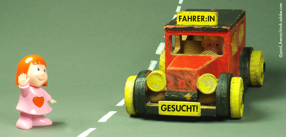 Spielzeugfiguren Mädchen und Auto mit Aufschrift Fahrer:in gesucht