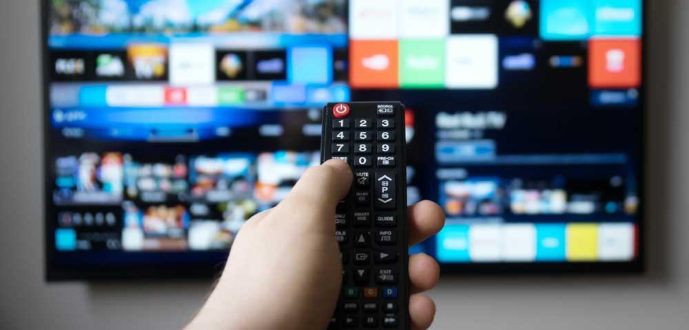 Foto Hand hält Fernbedienung im Hintergrund Fernseher 