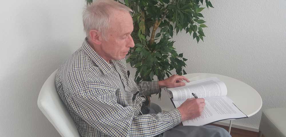 Werner Müller sitzt am Tisch vor seinem Manuskript