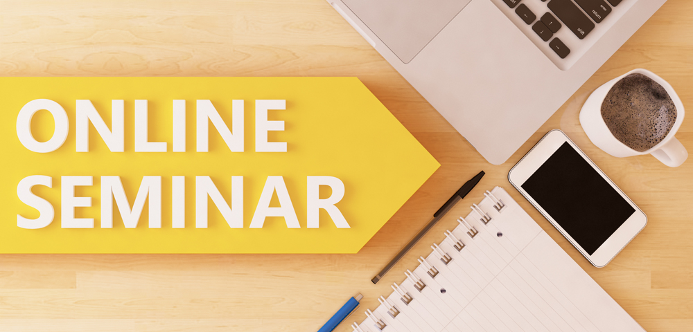 Foto zeigt Aufschrift Online-Seminar, Handy, Stift, Block, Laptop-Tastatur und Kaffeetasse
